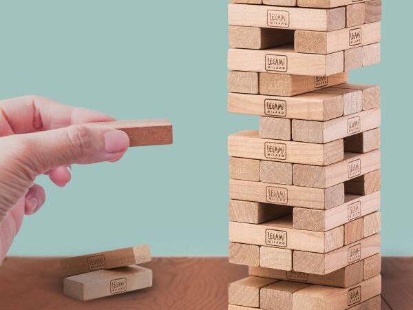 Detalhe de uma mão a remover um bloco do Jogo Tumbling Tower Legami.