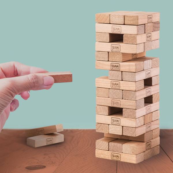 Detalhe de uma mão a remover um bloco do Jogo Tumbling Tower Legami.