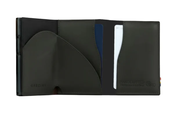 A Carteira Garzini MagSafe Metal Wallet Preta surge aberta sobre um fundo branco. Além disso, a Carteira Garzini MagSafe Metal Wallet Preta revela os seus compartimentos internos para cartões bancários.