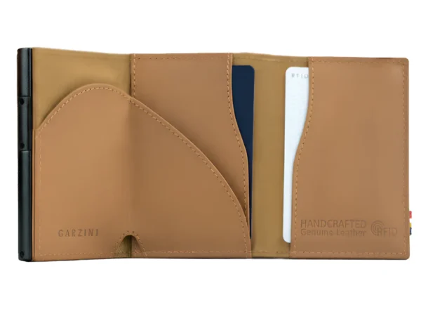 A Carteira Garzini MagSafe Metal Wallet Azul Camel surge aberta mostrando o seu interior tecnológico. Além disso, a Carteira Garzini MagSafe Metal Wallet Azul Camel destaca-se pela sua elegante textura de couro legítimo castanho.